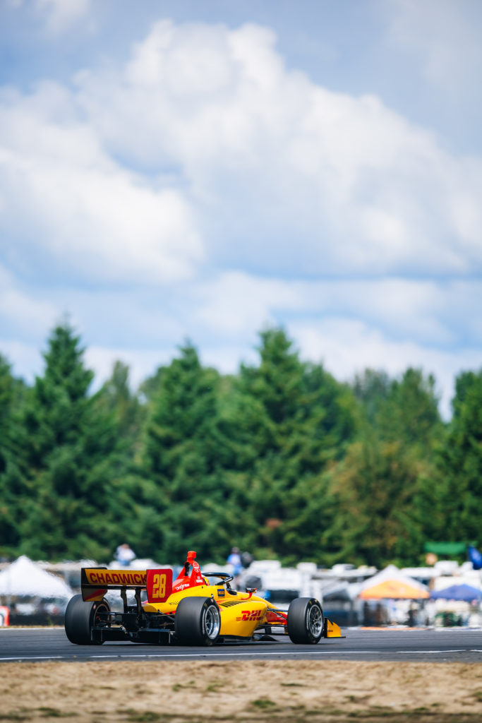 Photo of Jamie Chadwick car #28 racing on the track in the INDY CAR NXT road race in Portland